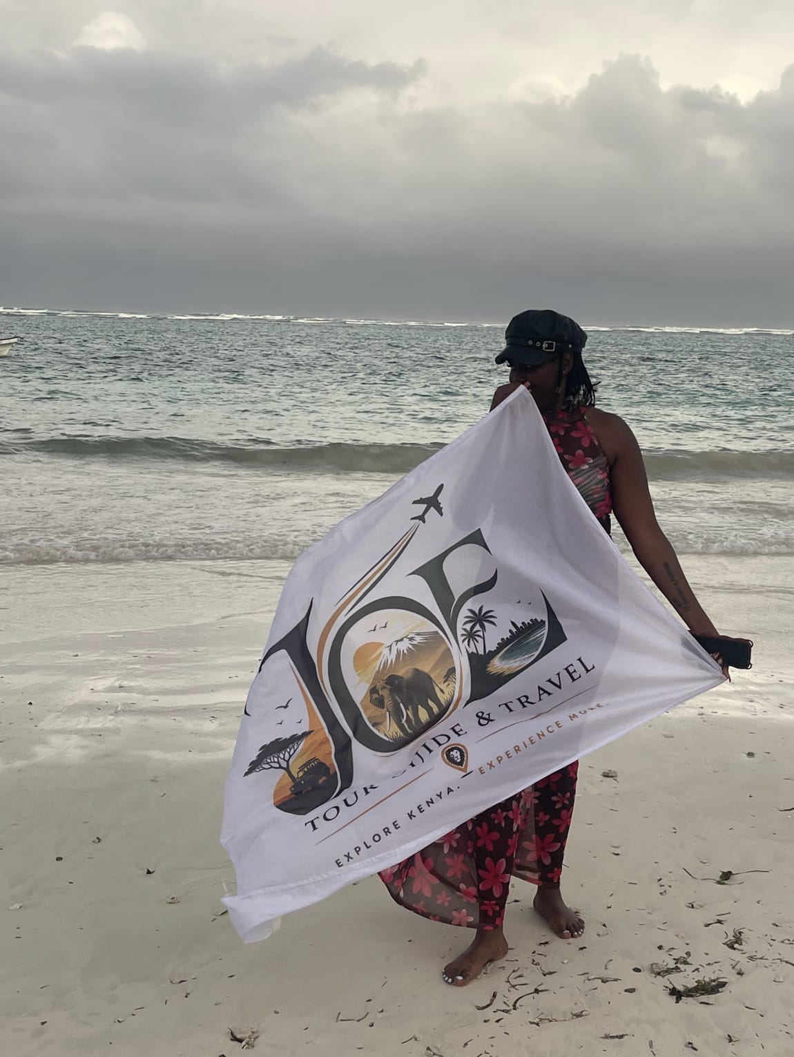Guest holding the JOE Tour Guide & Travel flag while looking out at the ocean