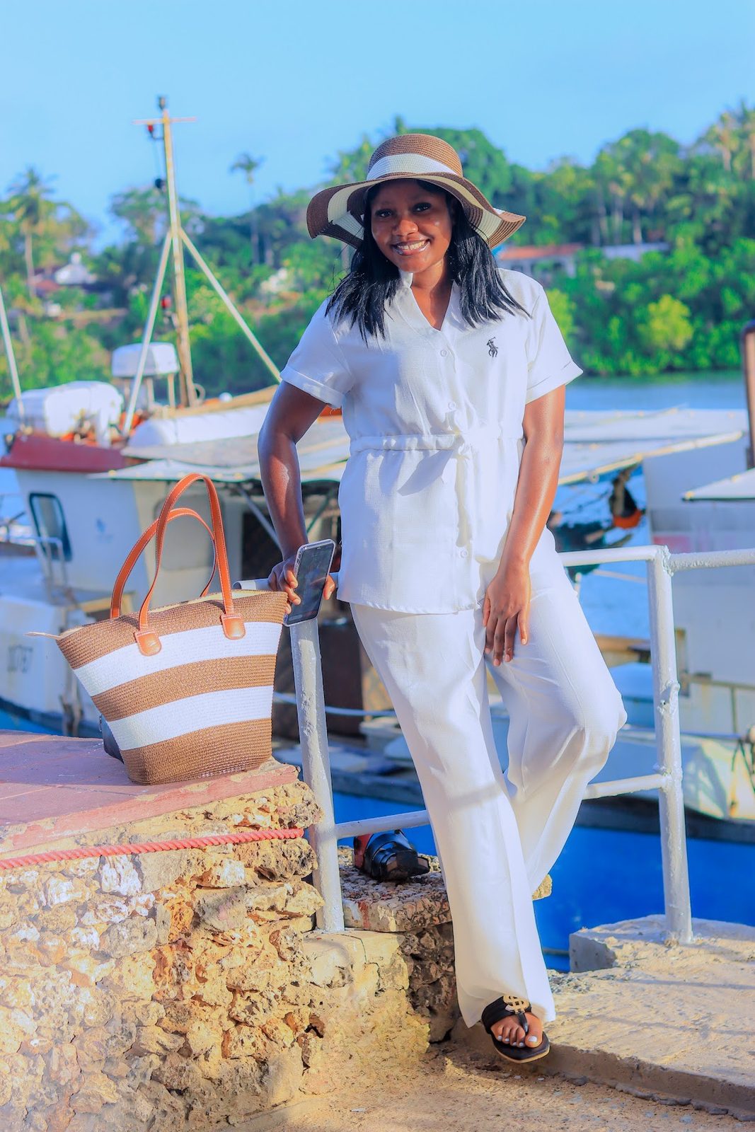 Guest in white with a beach bag by the boats