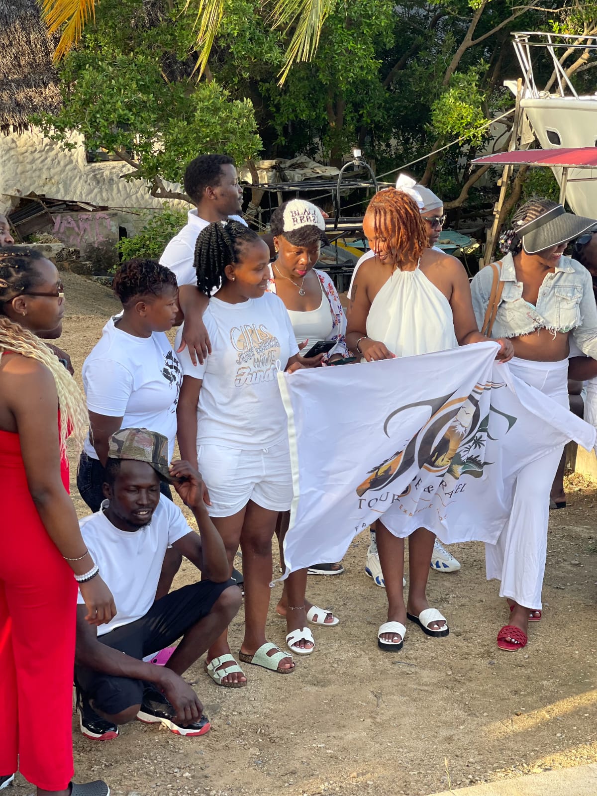 Guests holding the JOE Tour Guide & Travel flag at the creek gathering