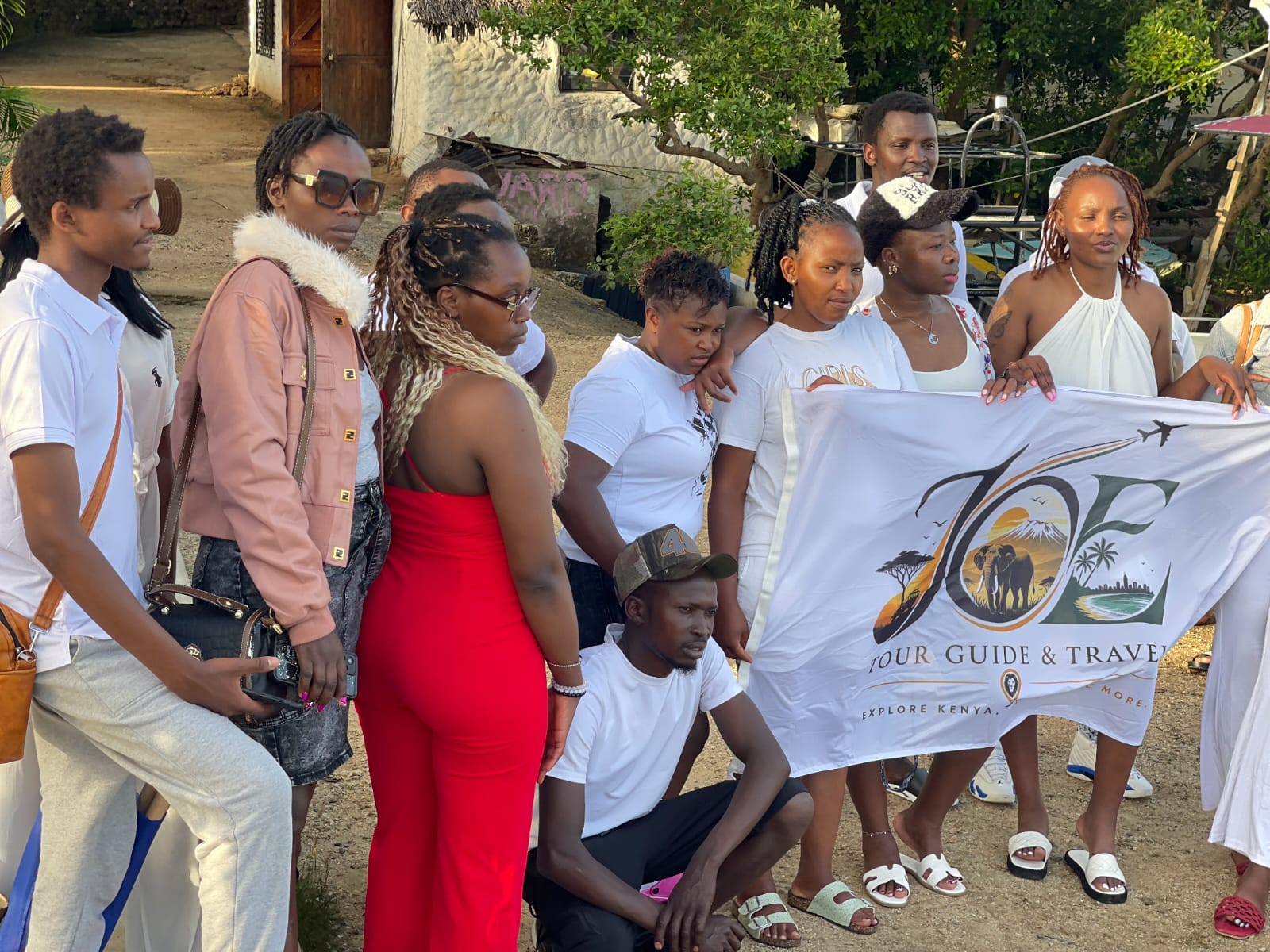 Guests posing with the JOE Tour Guide & Travel flag by the creek
