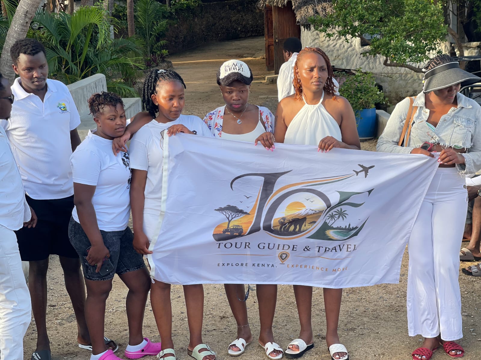 Guests holding the full JOE Tour Guide & Travel flag by the creek