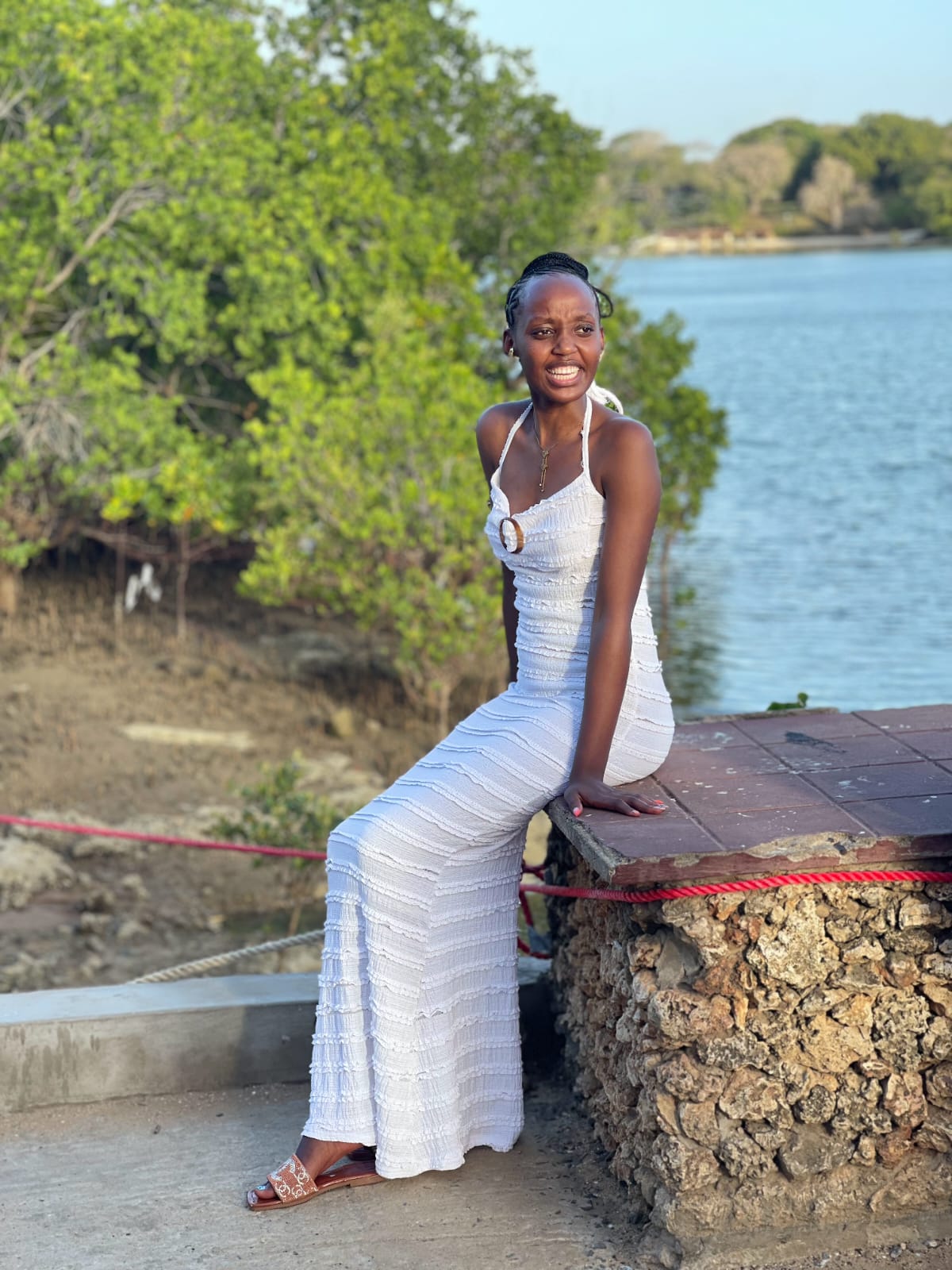 Guest posing on a coral-stone wall by the creek