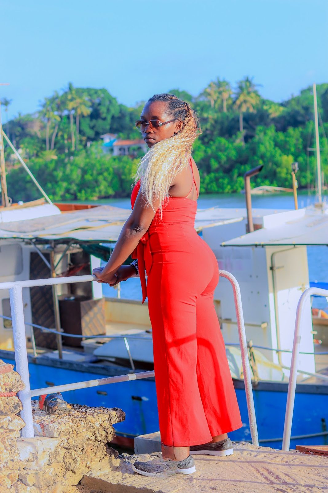 Guest in a red dress posing by the boats