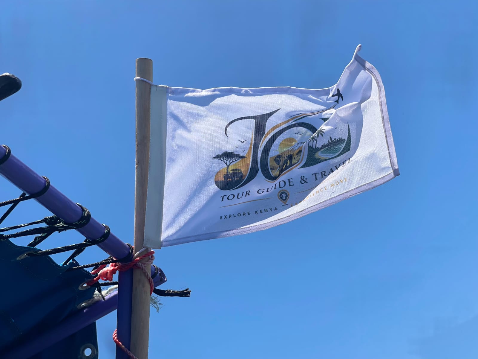 JOE Tour Guide & Travel flag flying from a boat mast against a blue sky