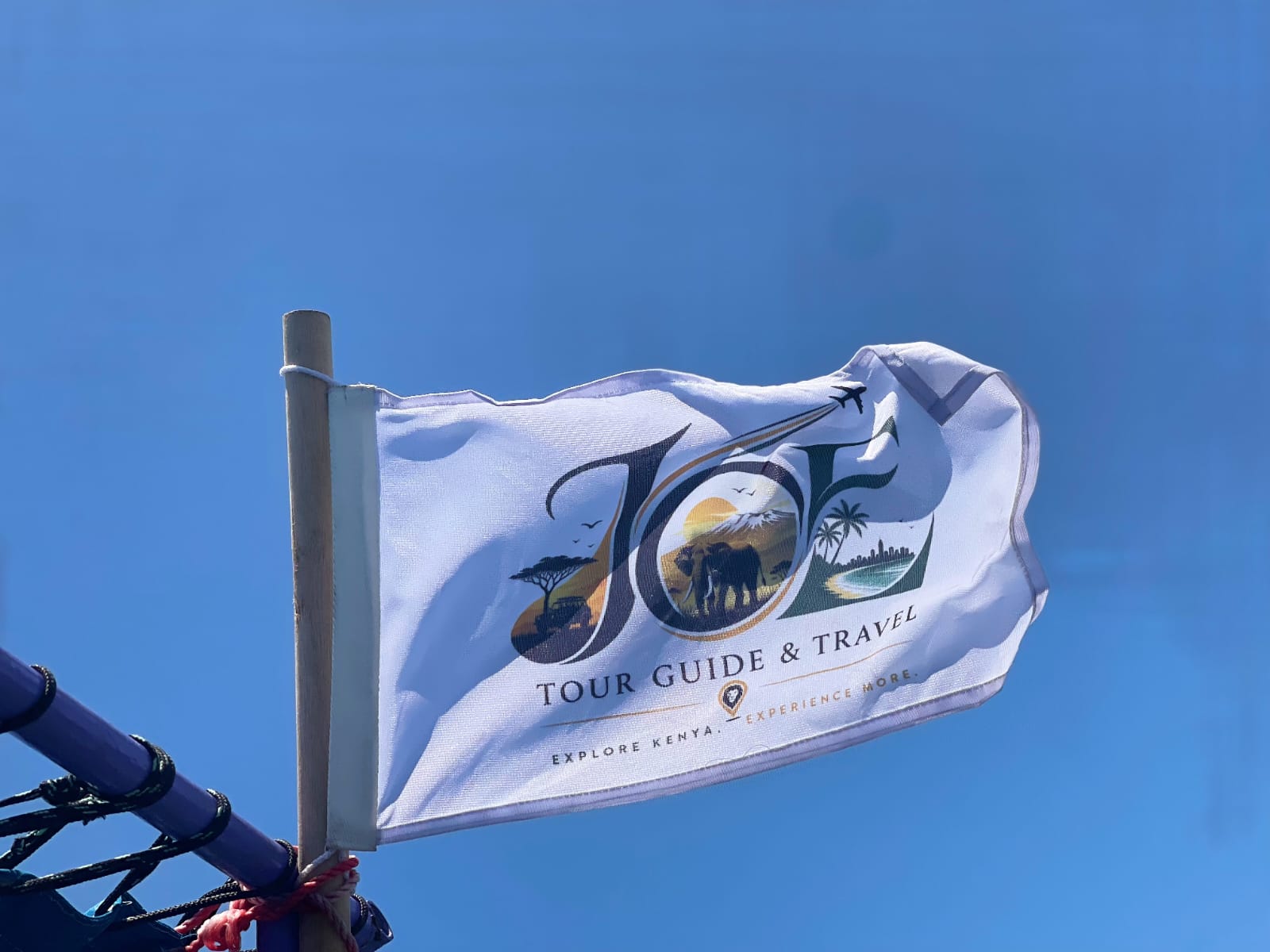 Close-up of the JOE Tour Guide & Travel flag against a clear blue sky