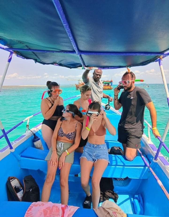 Guests putting on snorkel masks aboard the boat in turquoise water