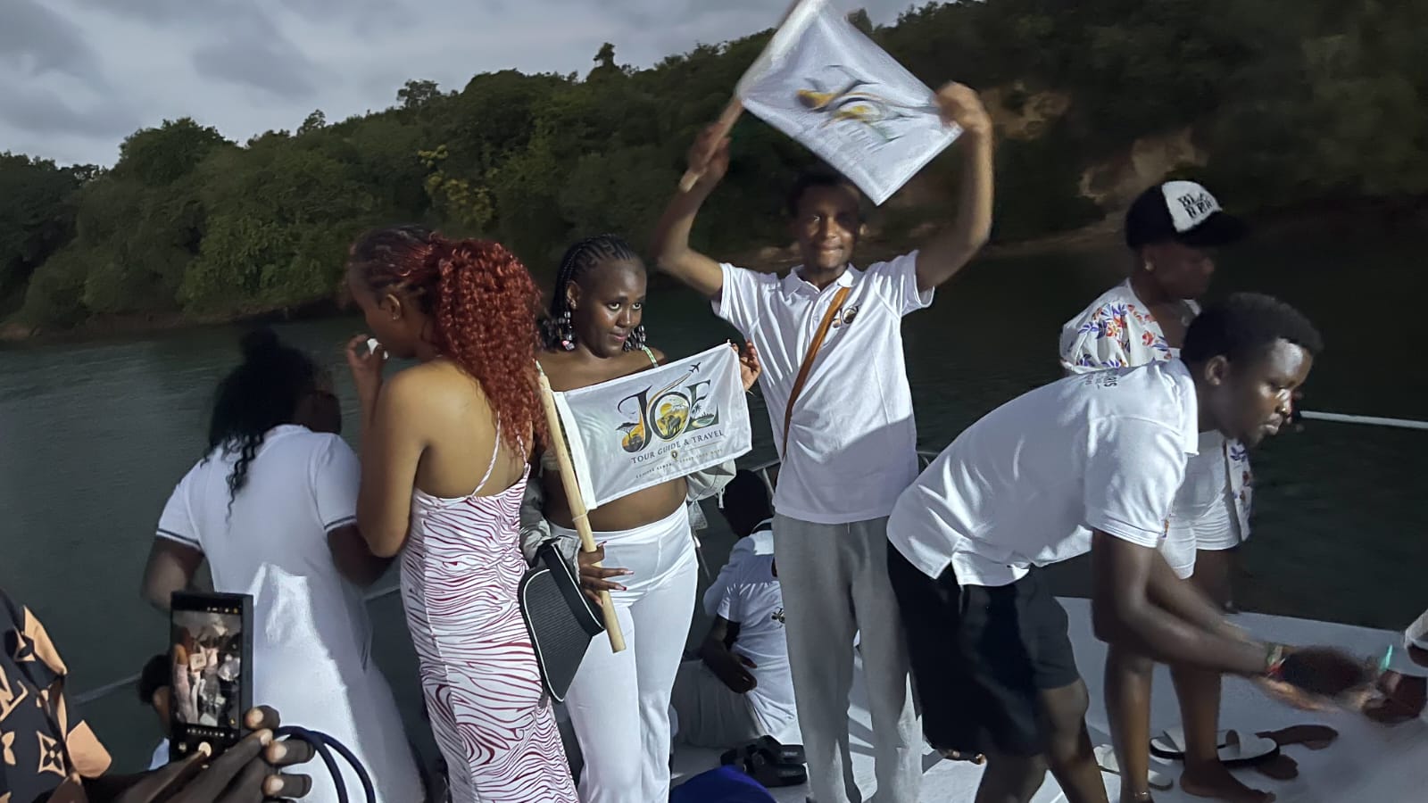 Guide holding the JOE Tour Guide & Travel banner aboard the sunset cruise boat