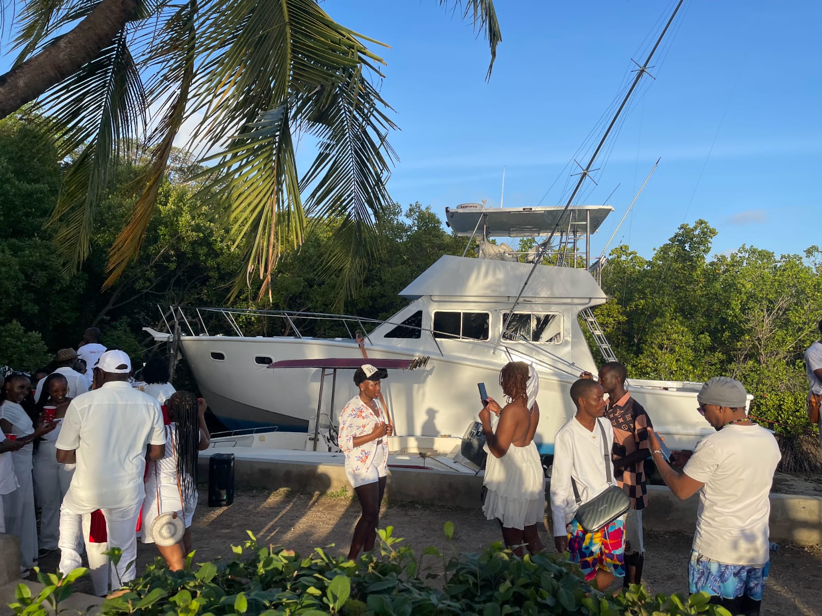 Guests in white attire gathered by a yacht at sunset in Mombasa