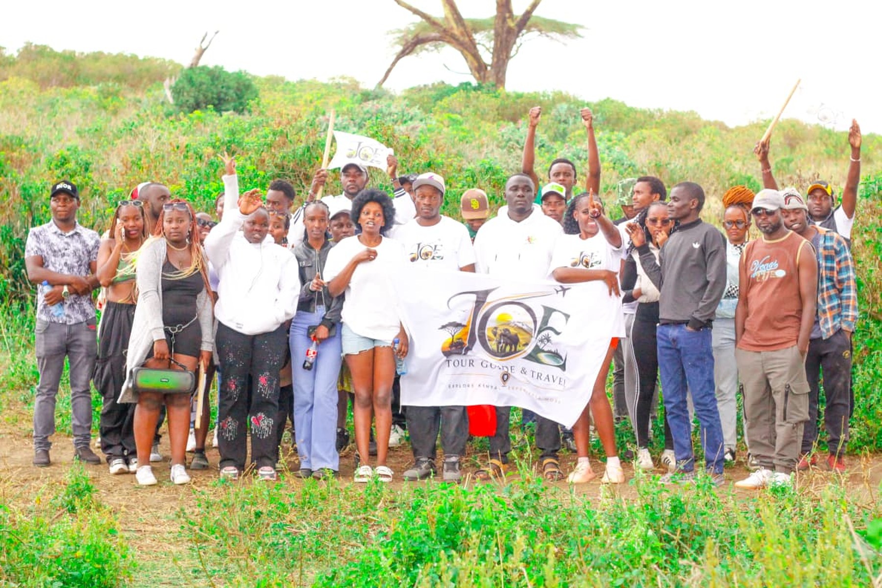 The JOE Tour Guide & Travel crew posing with the flag out on the Naivasha plains