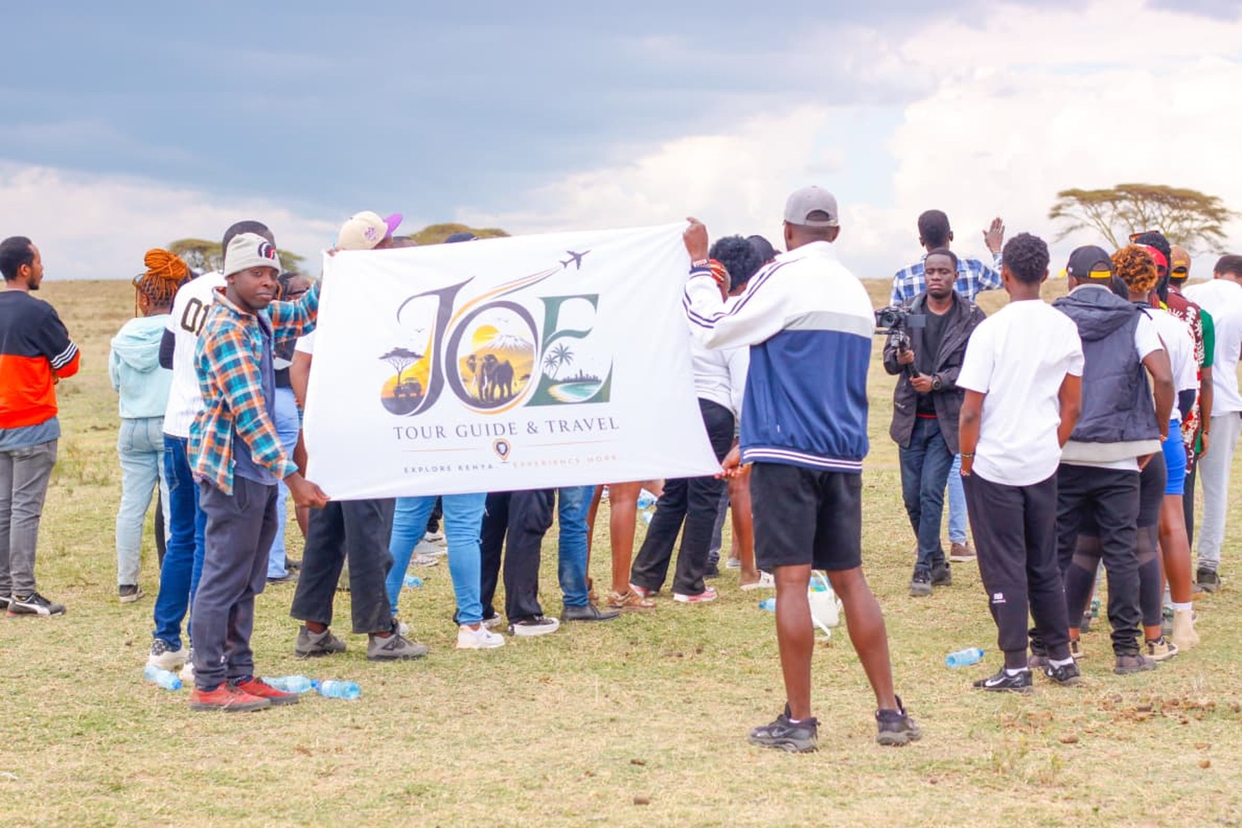 The group holding up the JOE Tour Guide & Travel flag on the Naivasha plains